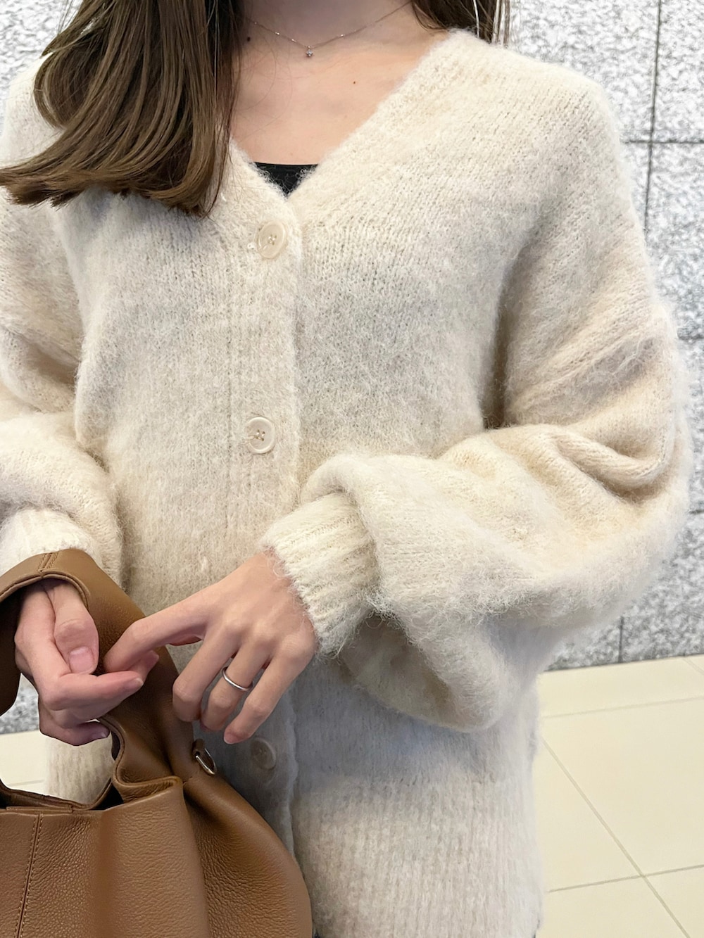 ホワイト系のカーディガン/ボレロ、ブラック系のスカート、ブラウン系のハンドバッグを着用したレディースの冬コーディネートの3枚目の写真