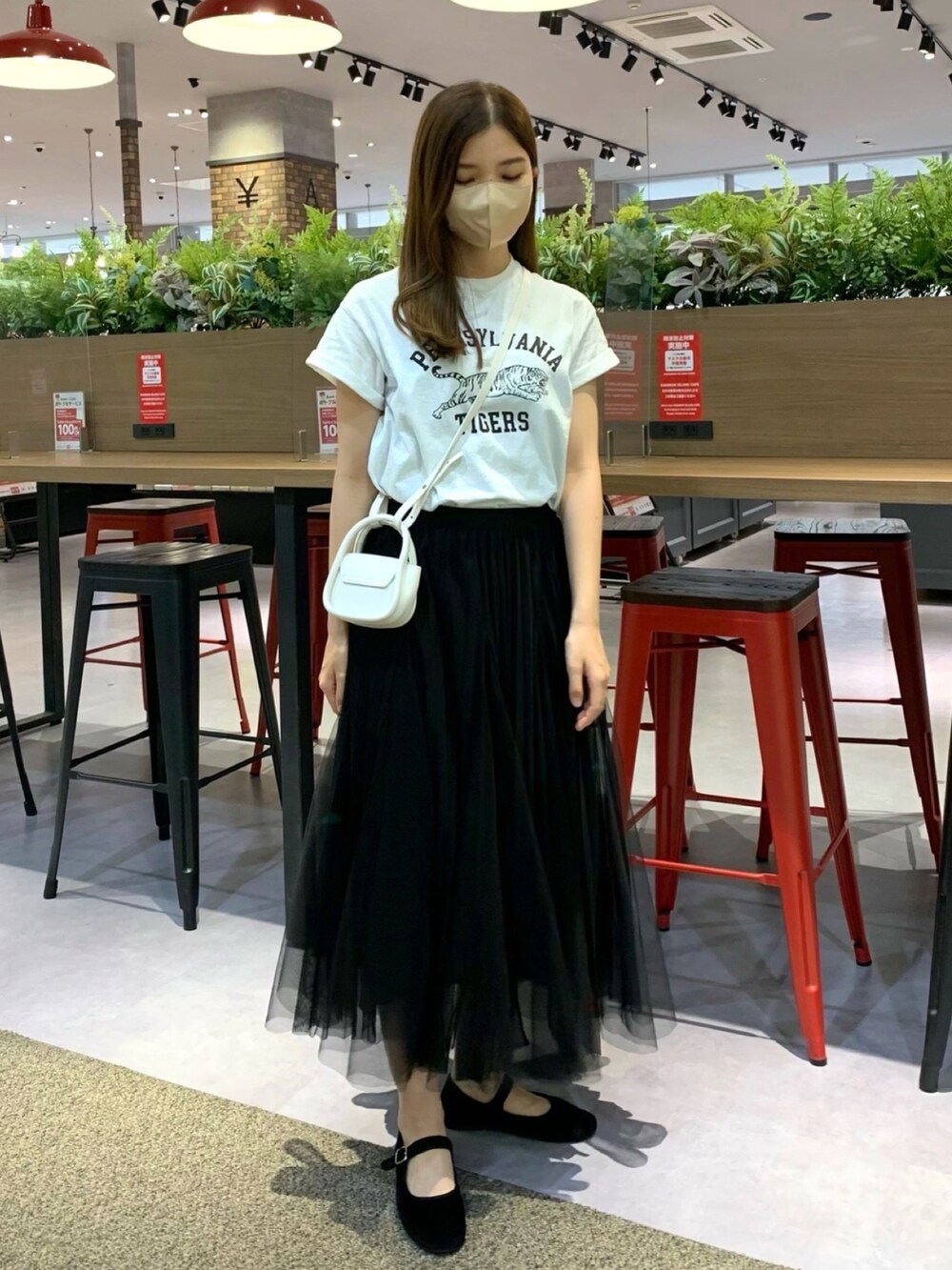 ホワイト系のTシャツ/カットソー、ブラック系のスカート、ホワイト系のショルダーバッグを着用したレディースの春コーディネートの2枚目の写真