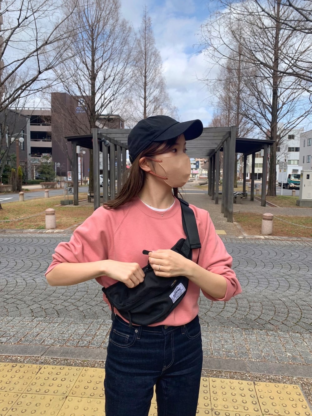 ピンク系のスウェット、ブルー系のデニムパンツ、ベージュ系のスニーカーを着用したレディースの冬コーディネートの2枚目の写真