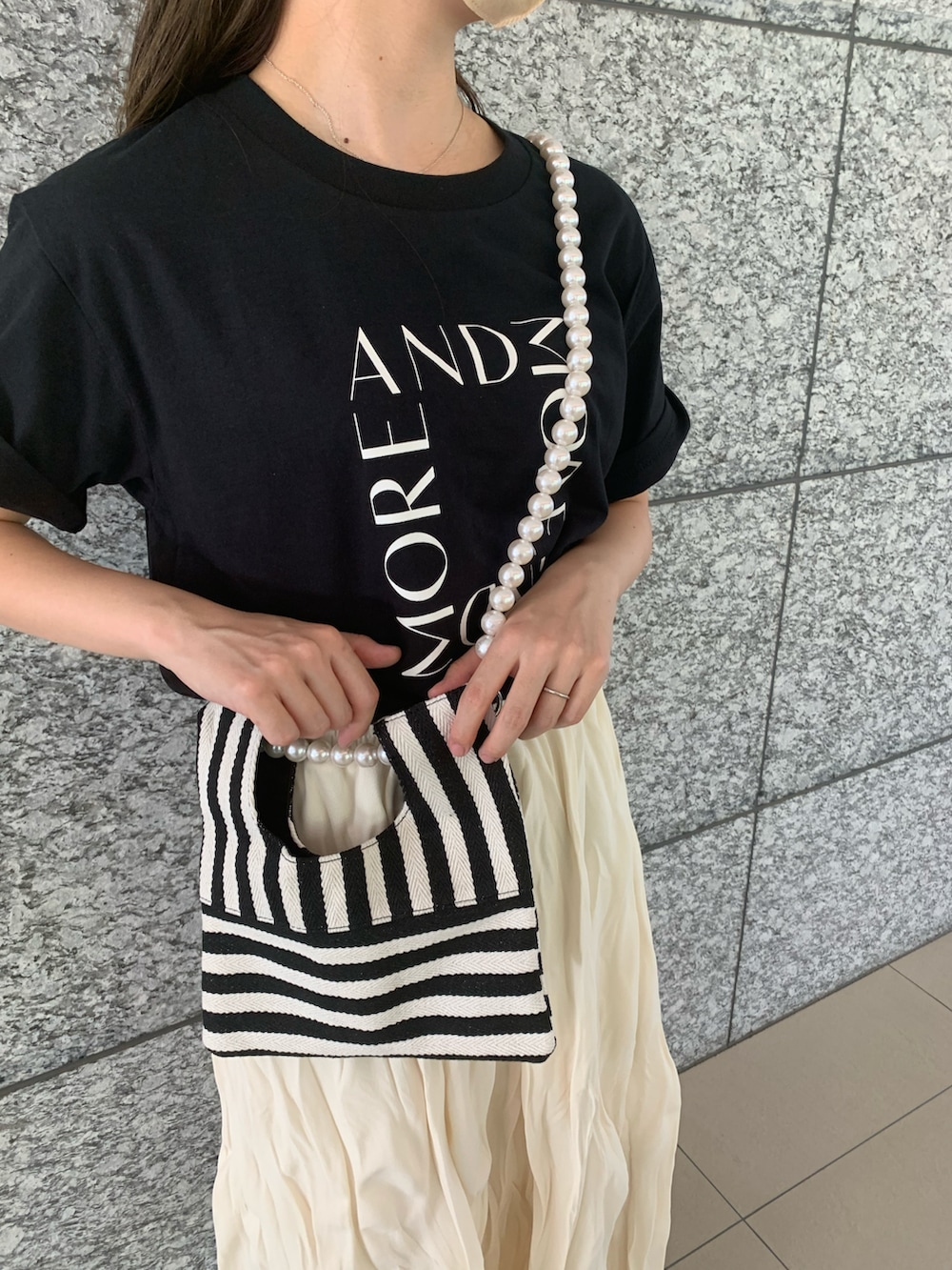 ブラック系のTシャツ/カットソー、ホワイト系のスカート、ブラック系のショルダーバッグを着用したレディースの夏コーディネートの2枚目の写真