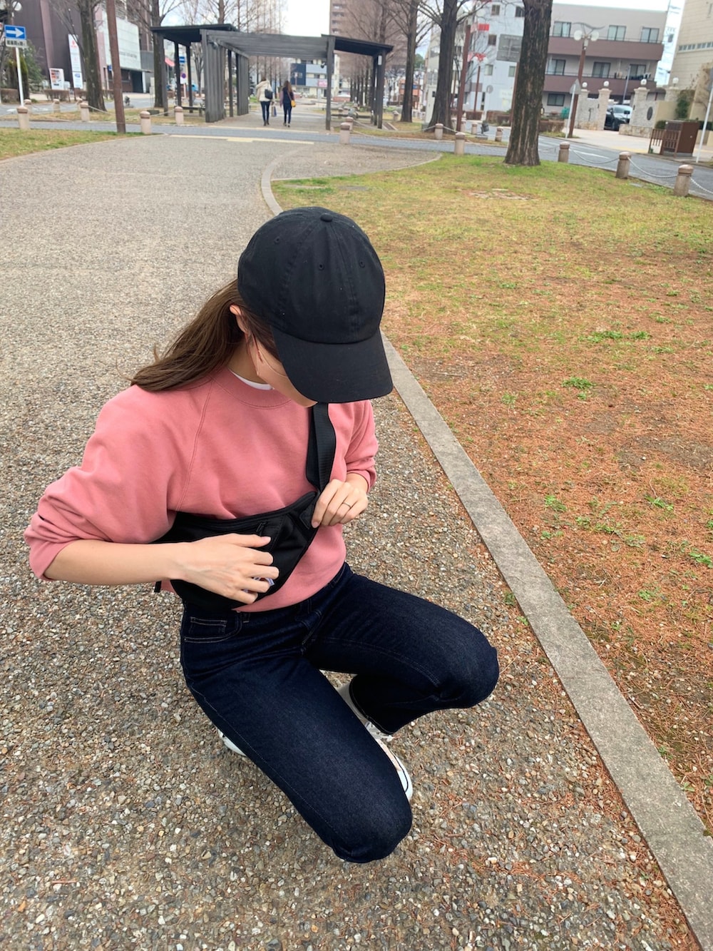 ピンク系のスウェット、ブルー系のデニムパンツ、ベージュ系のスニーカーを着用したレディースの冬コーディネートの3枚目の写真