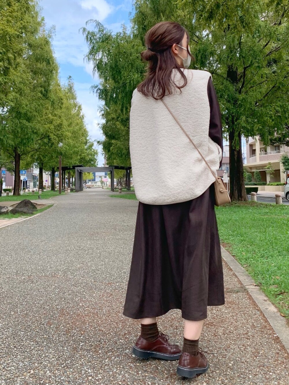 ホワイト系のベスト、ブラウン系のワンピース/ドレス、ベージュ系のショルダーバッグを着用したレディースの秋コーディネートの2枚目の写真