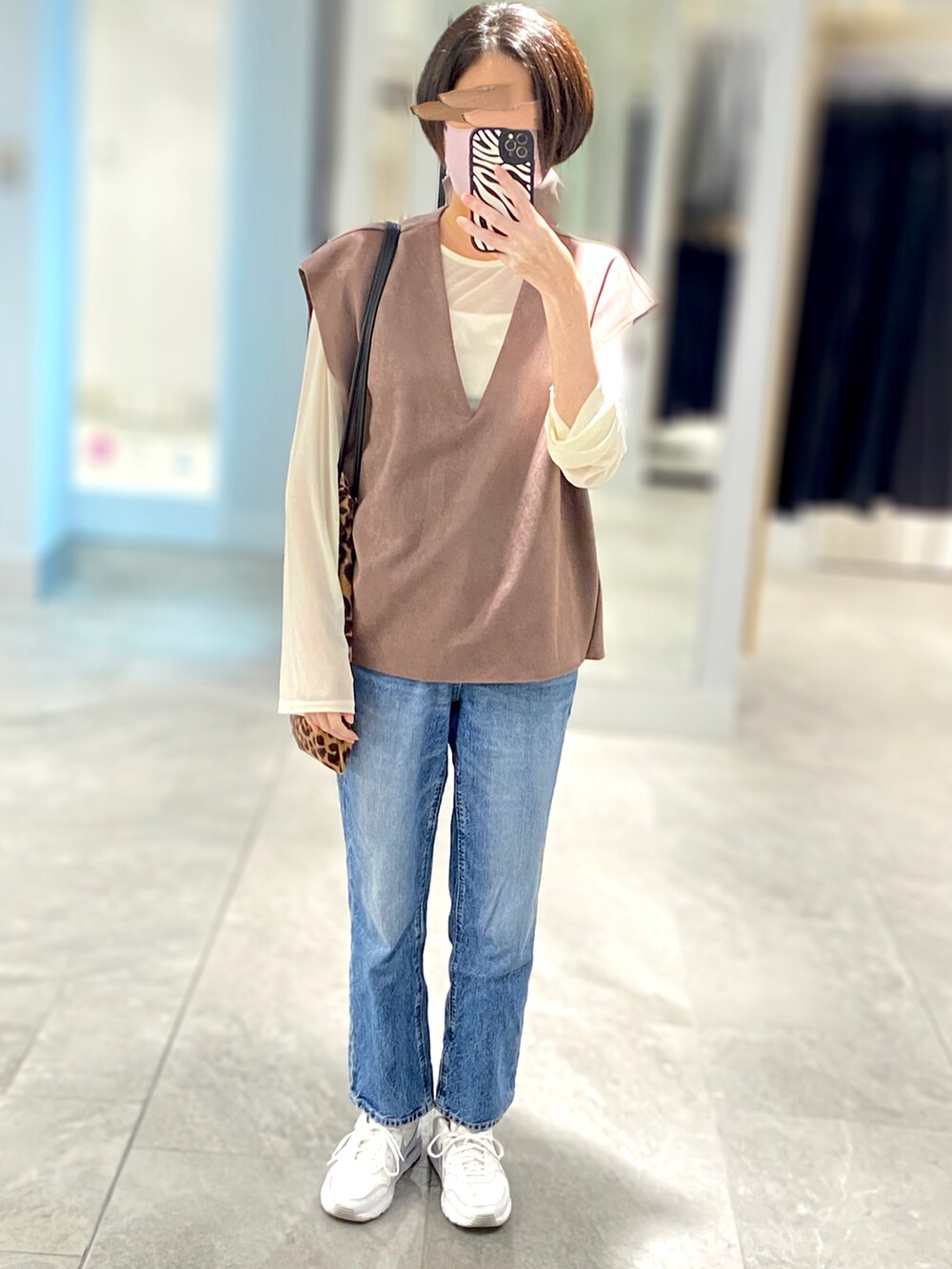 ブラウン系のベスト、その他のトートバッグ、ブルー系のデニムパンツを着用したレディースの秋コーディネートの2枚目の写真