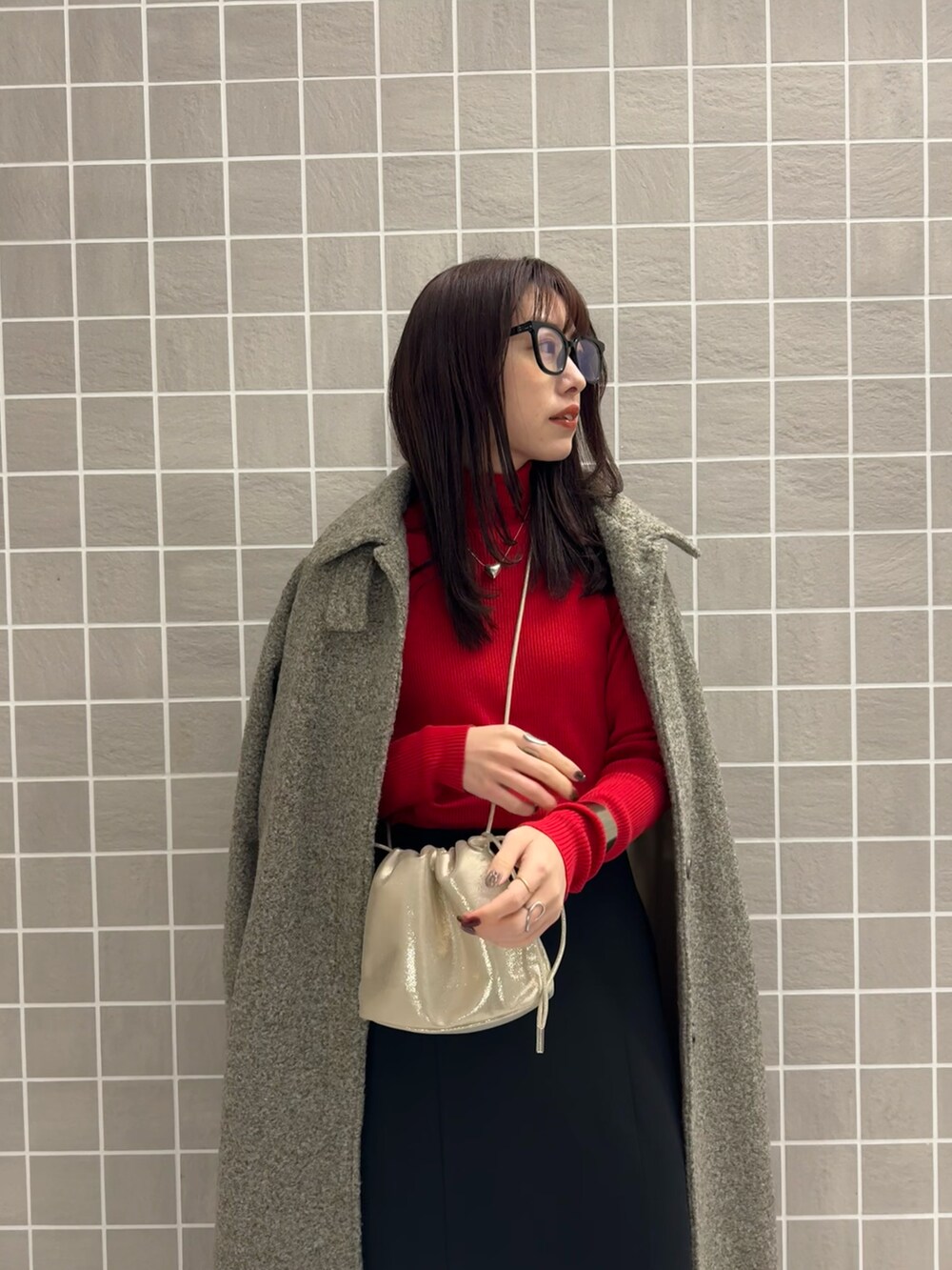 レッド系のニット/セーター、ブラック系のスカート、ベージュ系のその他アウターを着用したレディースの冬コーディネートの2枚目の写真