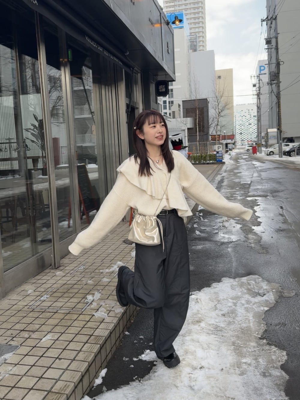 ゴールド系のショルダーバッグ、ホワイト系のニット/セーター、グレー系のスラックスを着用したレディースの冬コーディネートの2枚目の写真