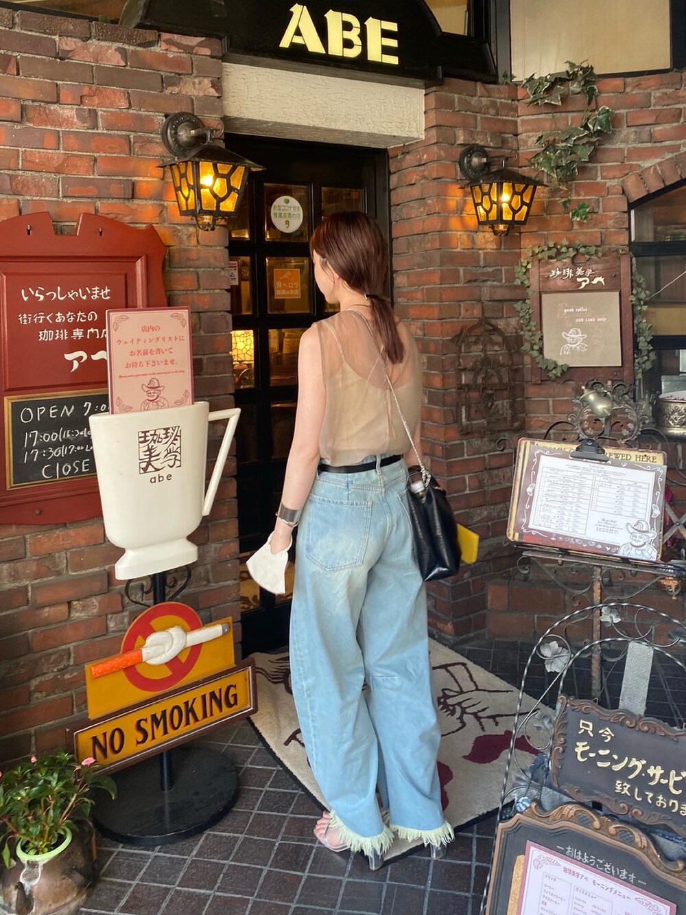 ベージュ系のトップス、ブルー系のデニムパンツを着用したレディースの夏コーディネートの2枚目の写真