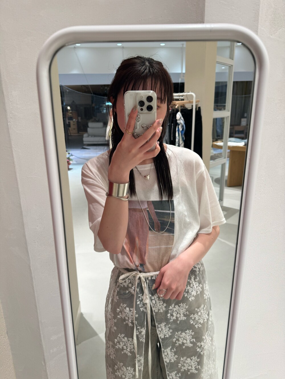 ブルー系のデニムパンツ、ピンク系のTシャツ/カットソー、ホワイト系のスカートを着用したレディースの春コーディネートの3枚目の写真