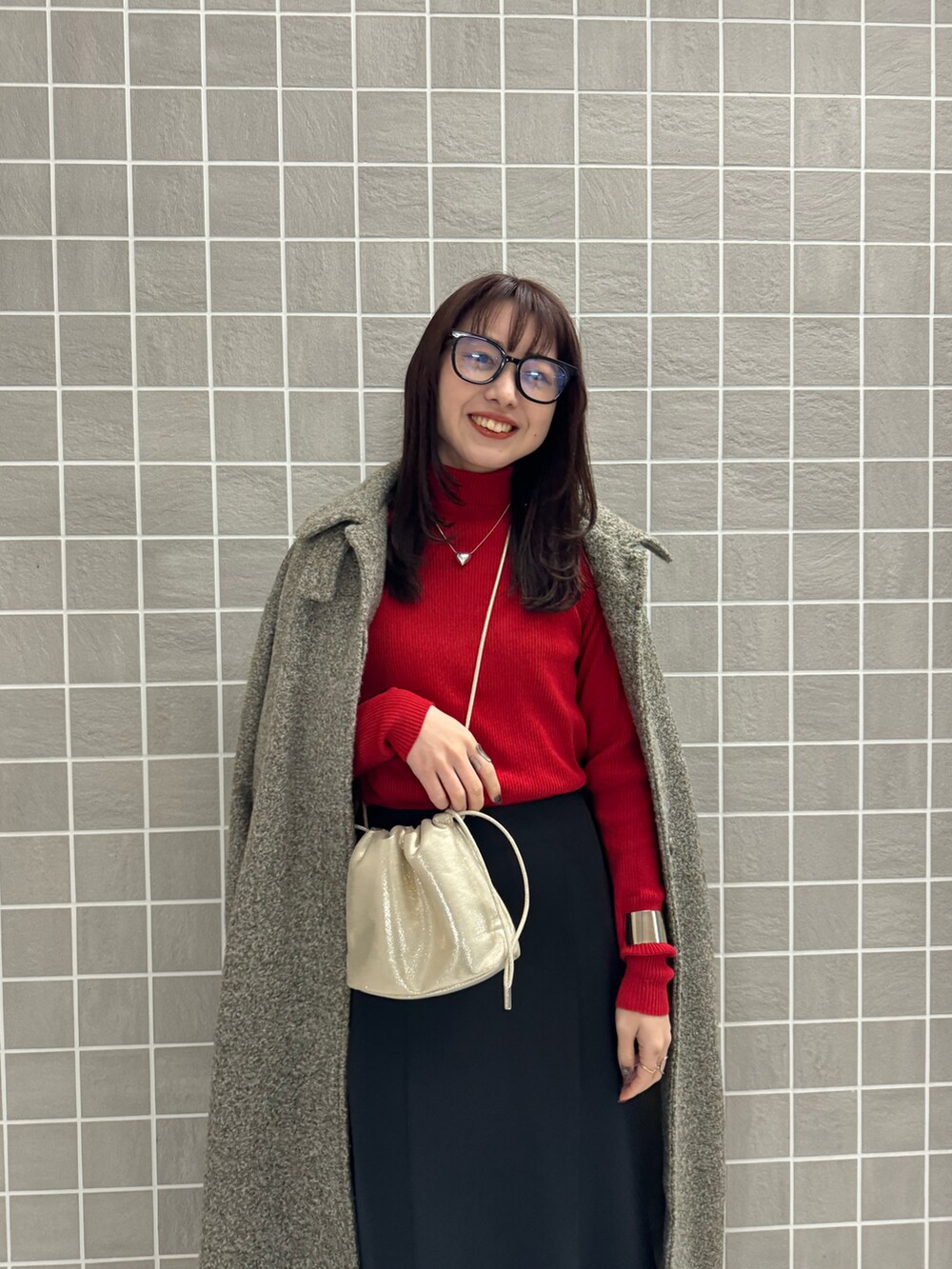 レッド系のニット/セーター、ブラック系のスカート、ベージュ系のその他アウターを着用したレディースの冬コーディネートの3枚目の写真
