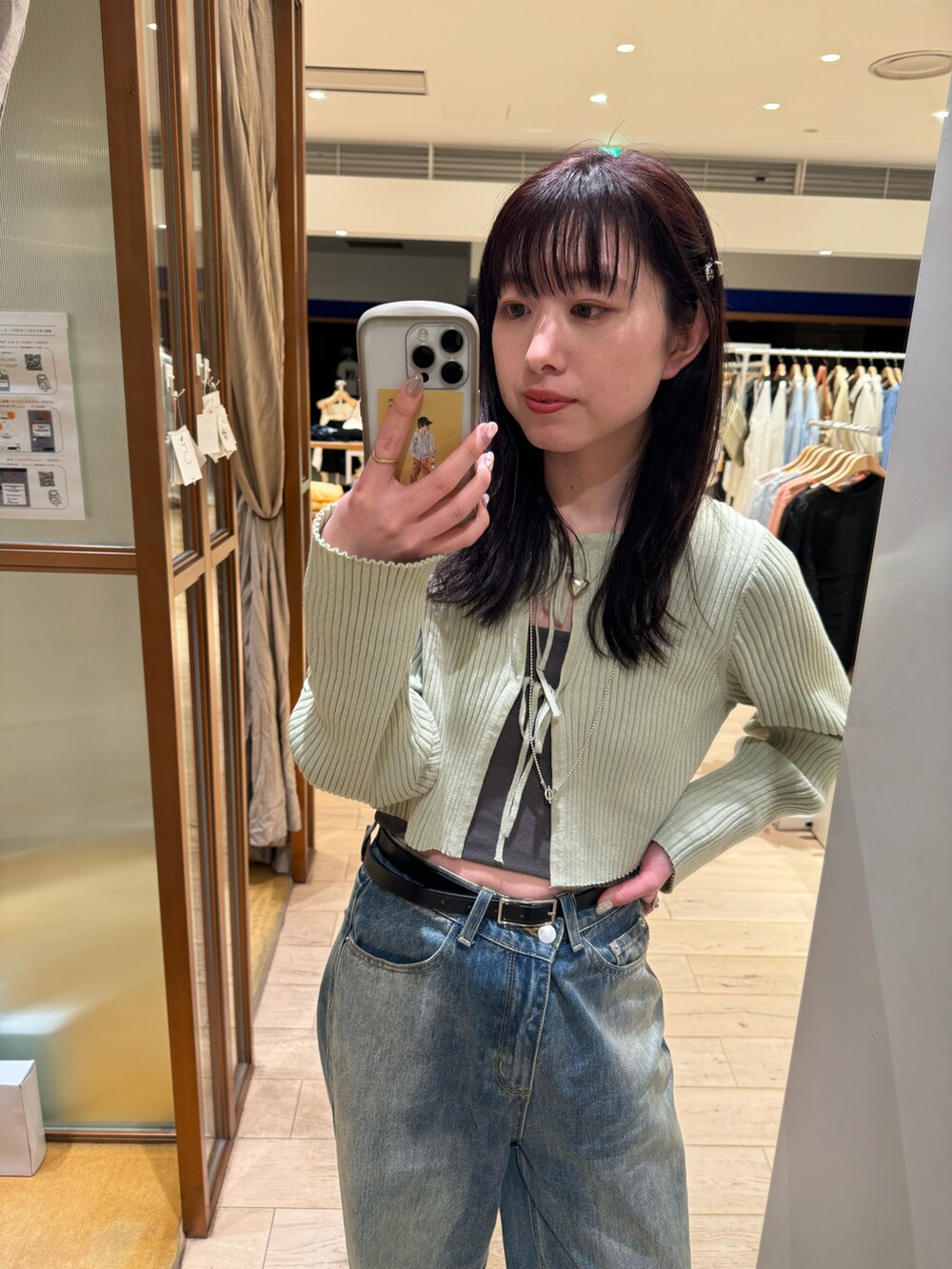 ブルー系のデニムパンツ、グリーン系のカーディガン/ボレロを着用したレディースの春コーディネートの2枚目の写真