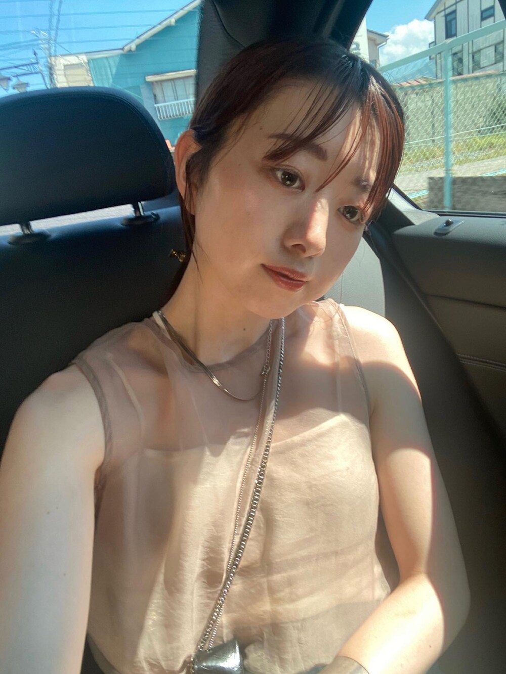 ベージュ系のトップス、ブルー系のデニムパンツを着用したレディースの夏コーディネートの3枚目の写真