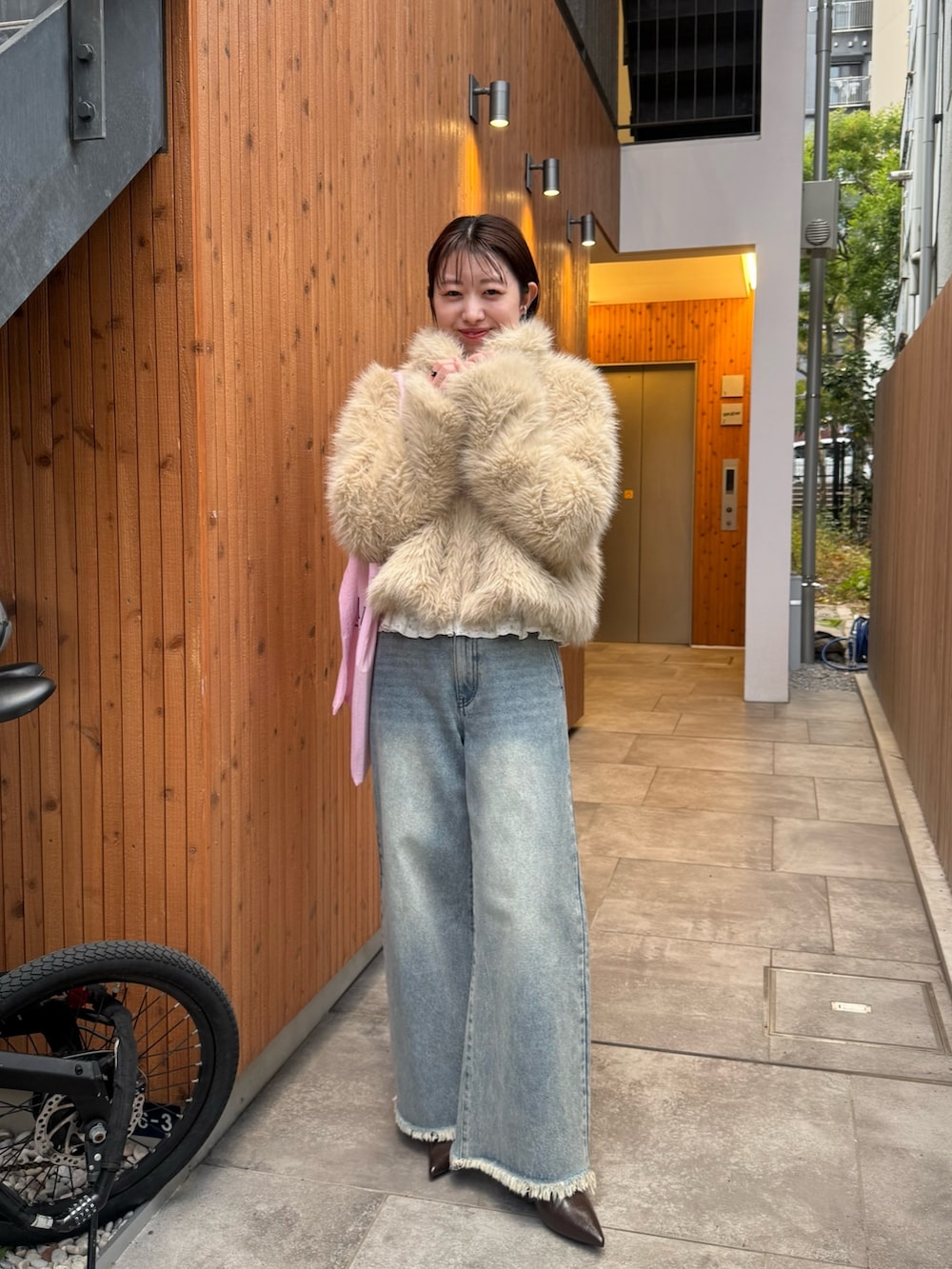 ベージュ系のその他アウター、ピンク系のトートバッグ、ブルー系のデニムパンツを着用したレディースの冬コーディネートの3枚目の写真