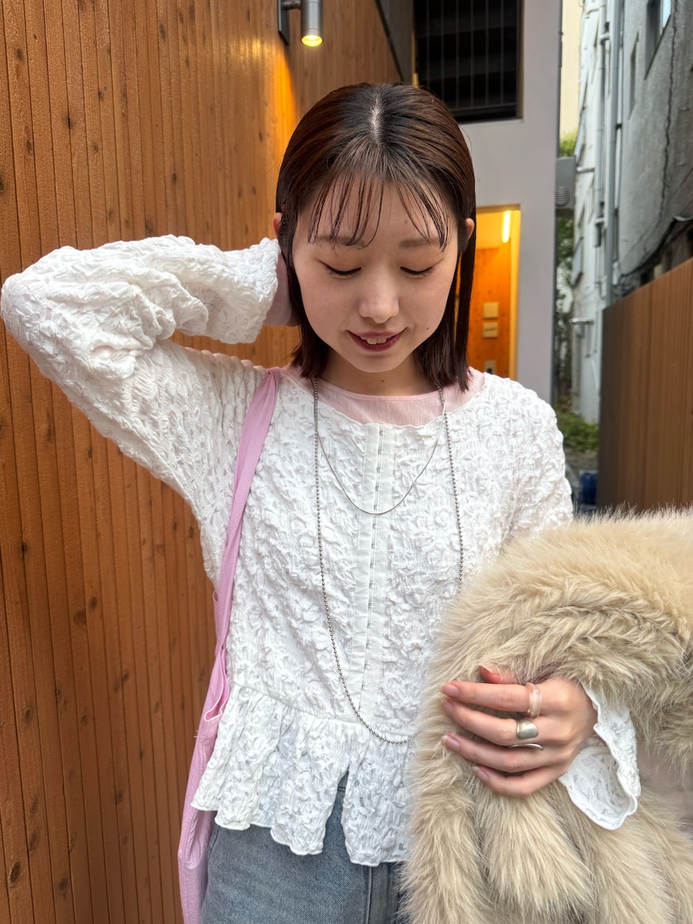 ベージュ系のその他アウター、ピンク系のトートバッグ、ブルー系のデニムパンツを着用したレディースの冬コーディネートの5枚目の写真