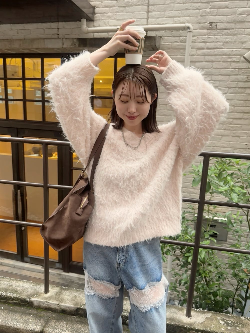 ピンク系のニット/セーター、ブルー系のデニムパンツ、ブラウン系のブーツを着用したレディースの秋コーディネートの3枚目の写真