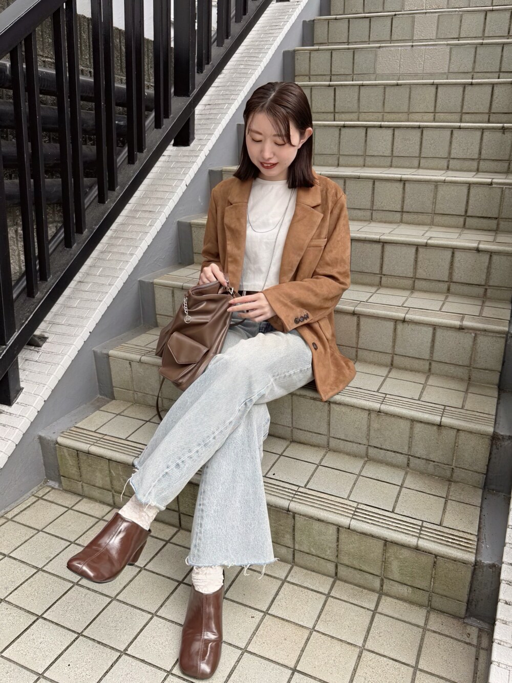 イエロー系のテーラードジャケット、イエロー系のトートバッグ、ブラウン系のブーツを着用したレディースの秋コーディネートの3枚目の写真