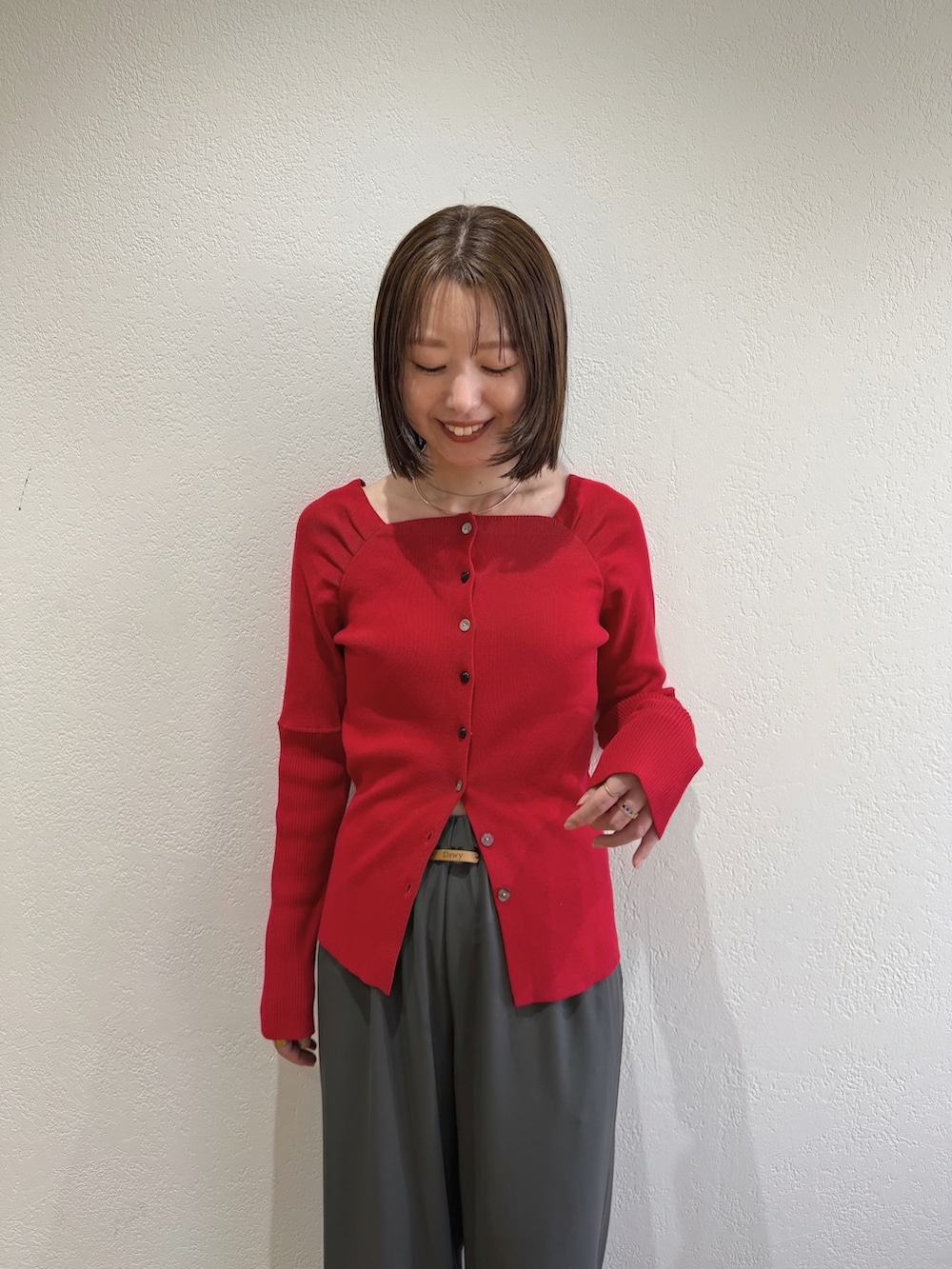 レッド系のニット/セーター、グレー系のスラックスを着用したレディースの夏コーディネートの2枚目の写真