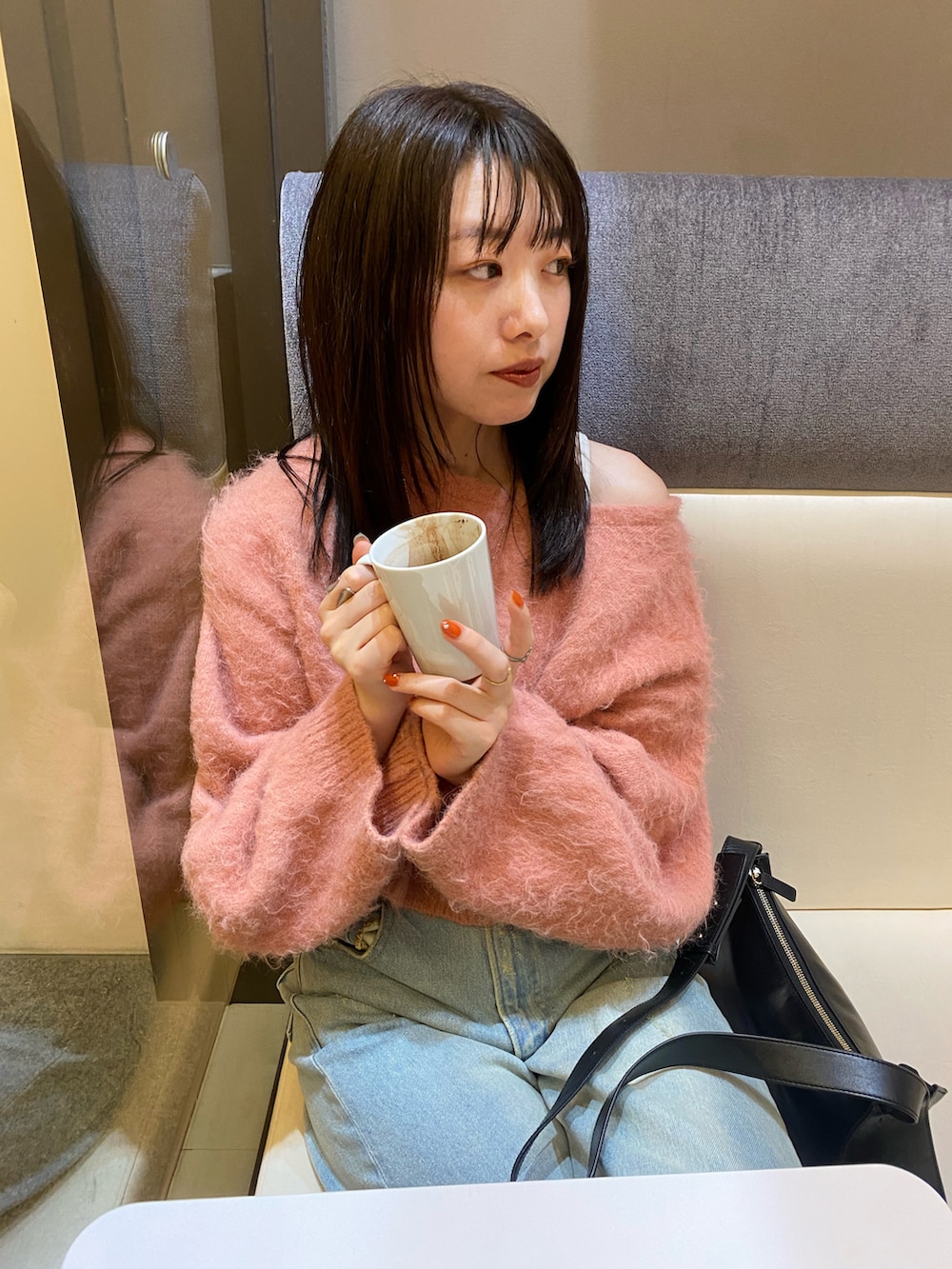 ブラック系のショルダーバッグ、ブルー系のデニムパンツ、ピンク系のニット/セーターを着用したレディースの冬コーディネートの2枚目の写真