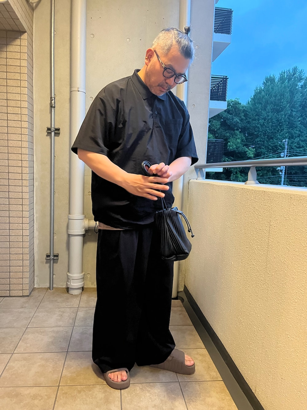 ブラック系のポロシャツ、ブラウン系のTシャツ/カットソー、ブラック系のカーゴパンツを着用したメンズの夏コーディネートの2枚目の写真