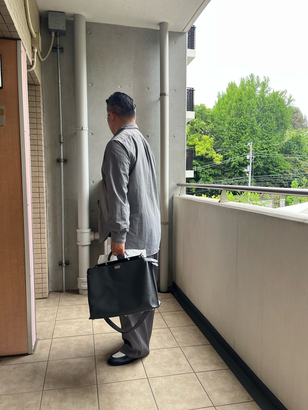 グレー系のビジネスバッグ、グレー系のスラックス、ブルー系のローファーを着用したメンズの春コーディネートの3枚目の写真