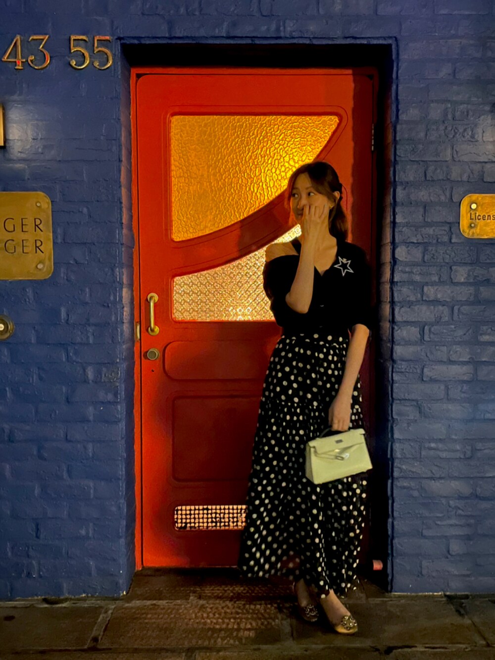 ブラック系のスカート、ブラック系のカーディガン/ボレロ、グリーン系のバッグを着用したレディースの春コーディネートの2枚目の写真