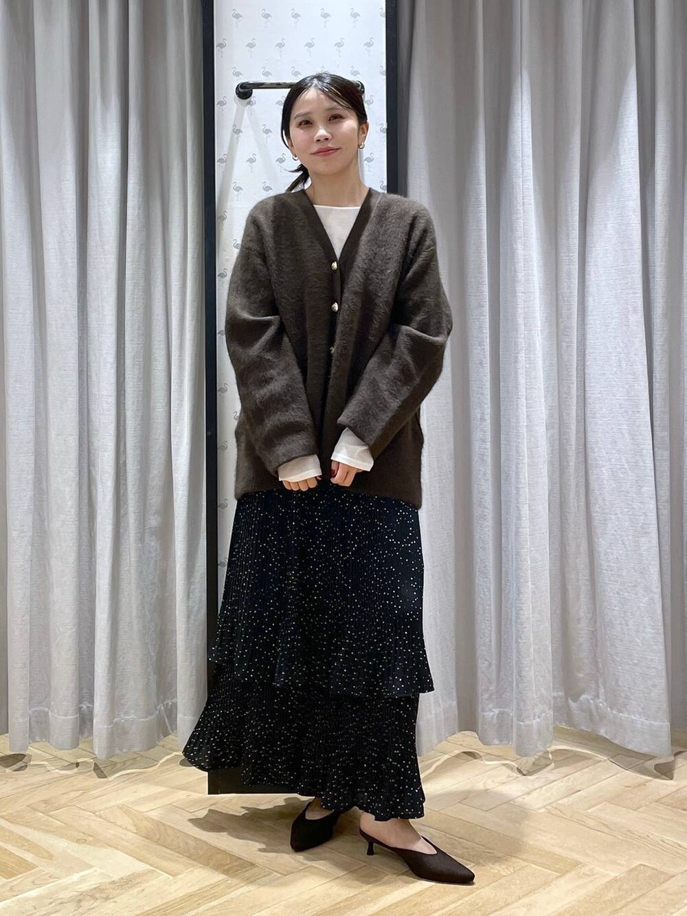 ブラウン系のカーディガン/ボレロ、ホワイト系のTシャツ/カットソー、グレー系のスカートを着用したレディースの秋コーディネートの5枚目の写真