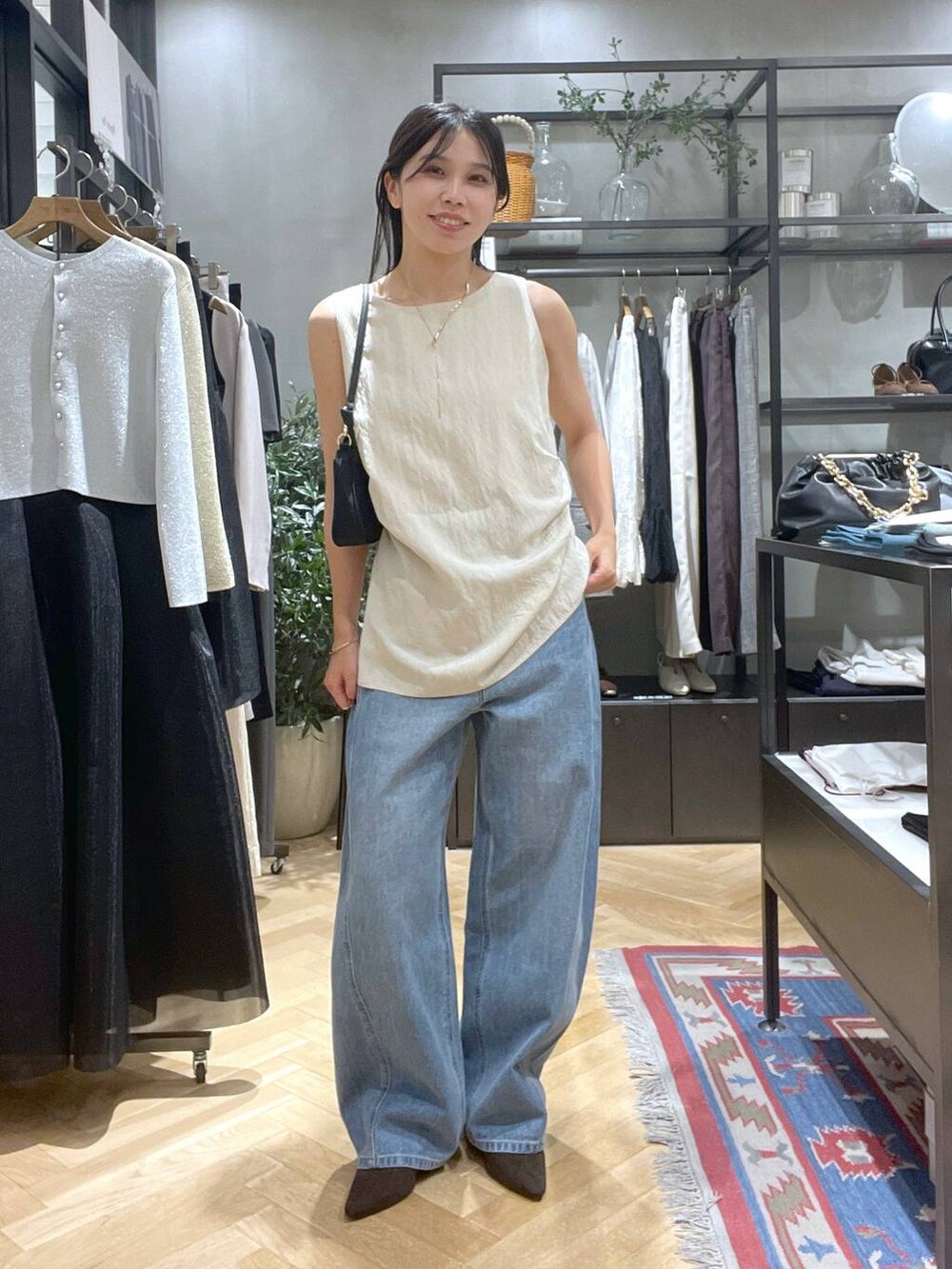 ブルー系のデニムパンツ、ブラウン系のパンプス、ブラック系のショルダーバッグを着用したレディースの夏コーディネートの4枚目の写真