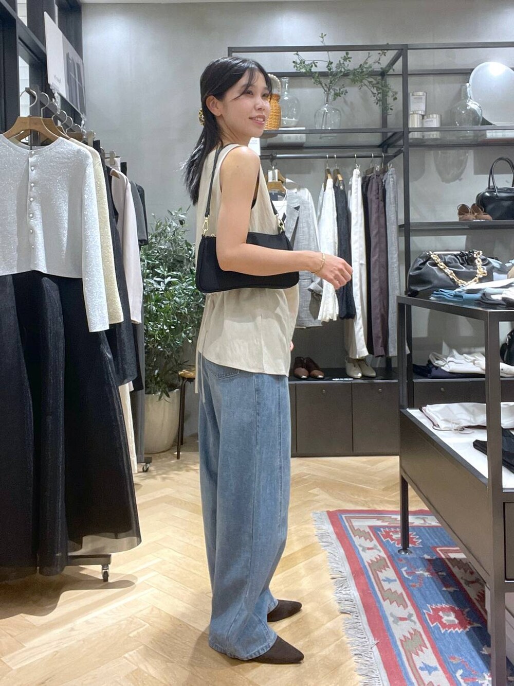 ブルー系のデニムパンツ、ブラウン系のパンプス、ブラック系のショルダーバッグを着用したレディースの夏コーディネートの2枚目の写真