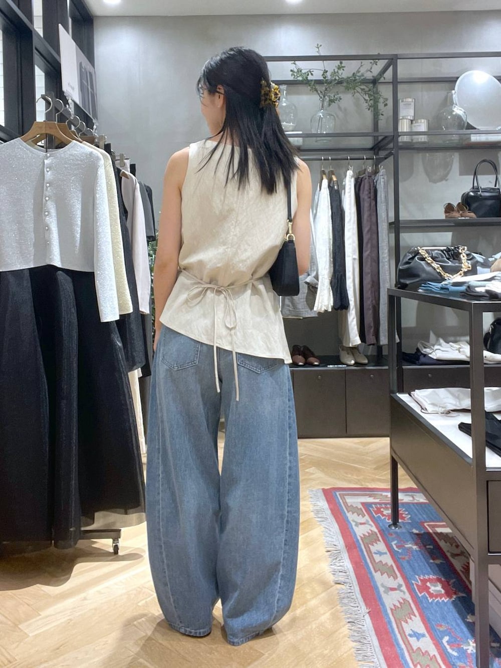 ブルー系のデニムパンツ、ブラウン系のパンプス、ブラック系のショルダーバッグを着用したレディースの夏コーディネートの3枚目の写真