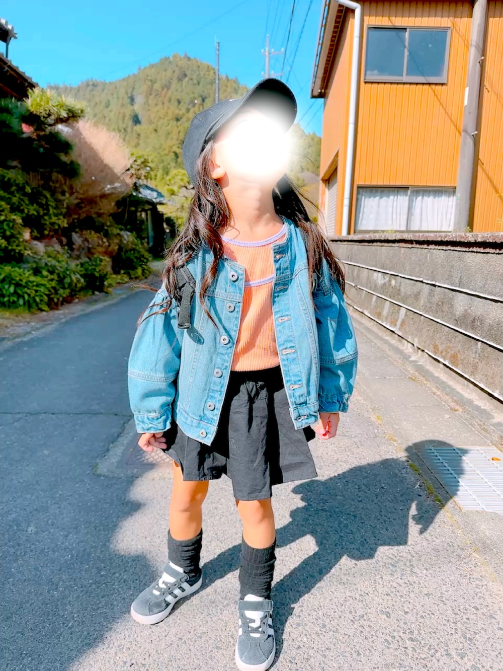 ブルー系のデニムジャケット、ブラック系のスニーカー、オレンジ系のTシャツ/カットソーを着用したキッズの春コーディネートの4枚目の写真