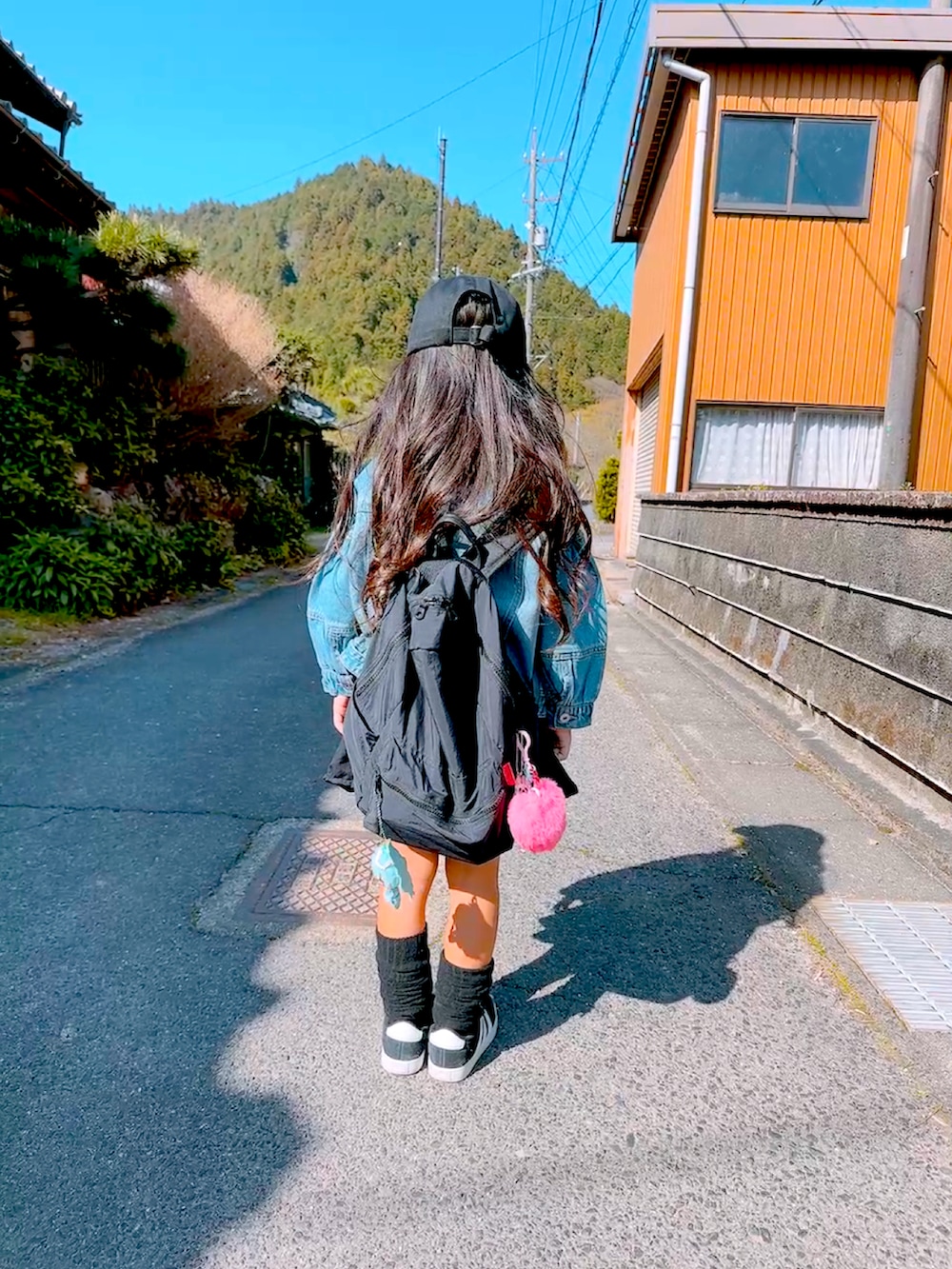 ブルー系のデニムジャケット、ブラック系のスニーカー、オレンジ系のTシャツ/カットソーを着用したキッズの春コーディネートの2枚目の写真