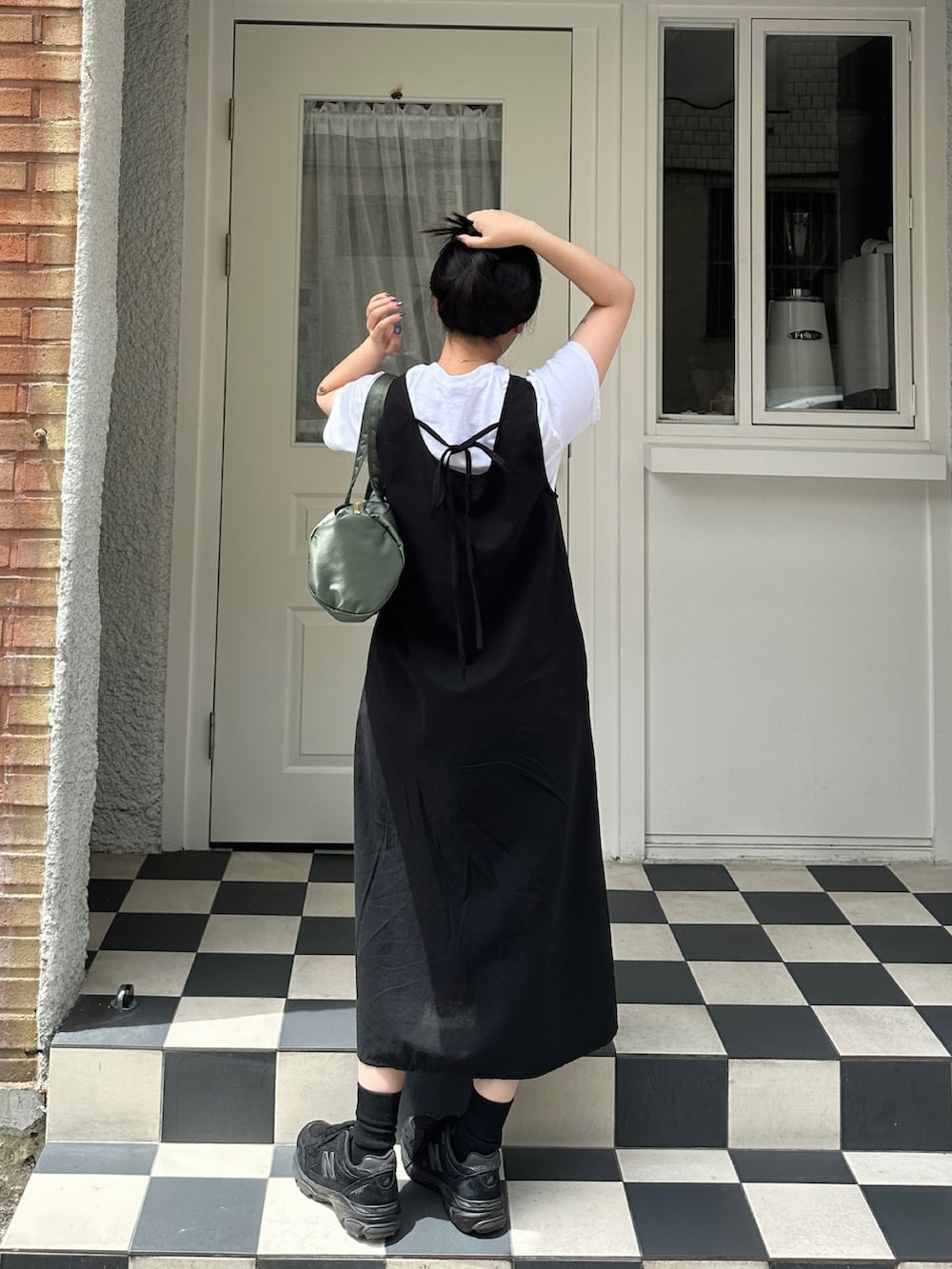 ブラック系のワンピース、ブラック系のスニーカー、グリーン系のボストンバッグを着用したレディースの夏コーディネートの2枚目の写真