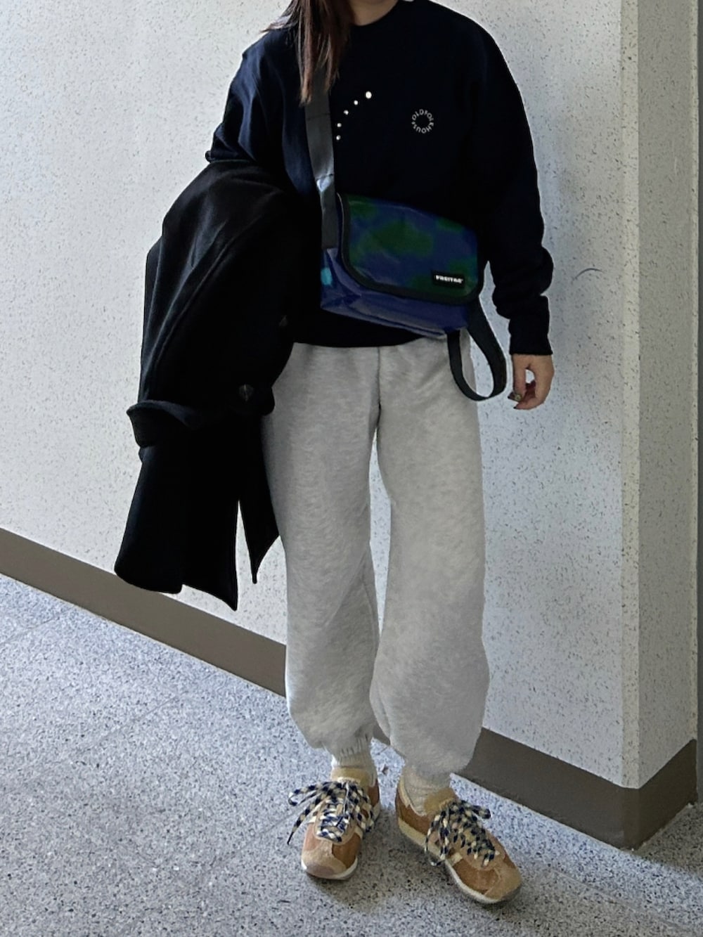 ホワイト系のスウェットパンツ、イエロー系のスニーカー、ブルー系のショルダーバッグを着用したレディースの冬コーディネートの2枚目の写真