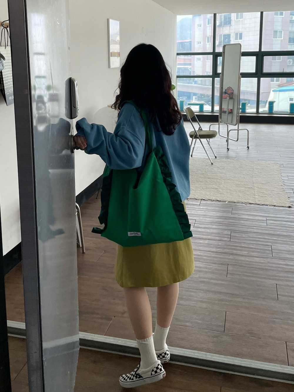 ブラック系のスリッポン、グリーン系のショルダーバッグ、グリーン系のスカートを着用したレディースの夏コーディネートの3枚目の写真