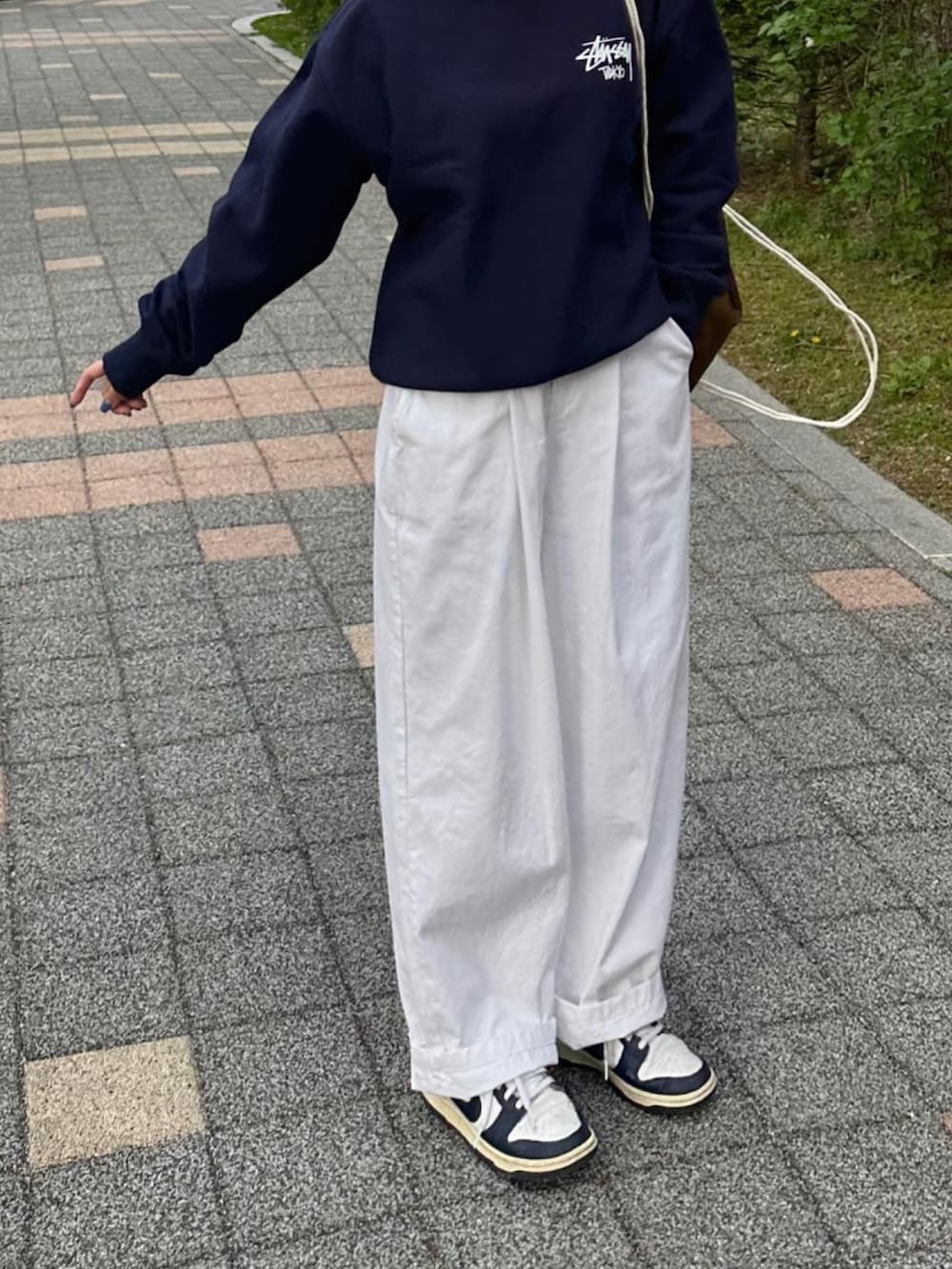 ブルー系のスウェット、ブラウン系のバックパック/リュック、ホワイト系のチノパンツを着用したレディースの春コーディネートの2枚目の写真