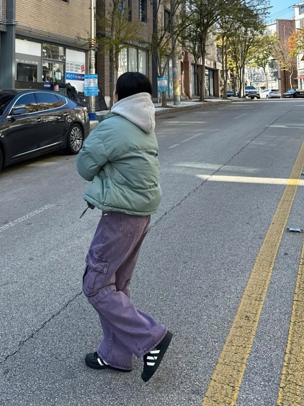 グリーン系のダウンジャケット/コート、パープル系のカーゴパンツ、ブラック系のスニーカーを着用したレディースの秋コーディネートの2枚目の写真