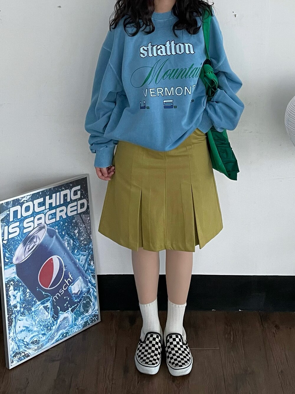 ブラック系のスリッポン、グリーン系のショルダーバッグ、グリーン系のスカートを着用したレディースの夏コーディネートの2枚目の写真