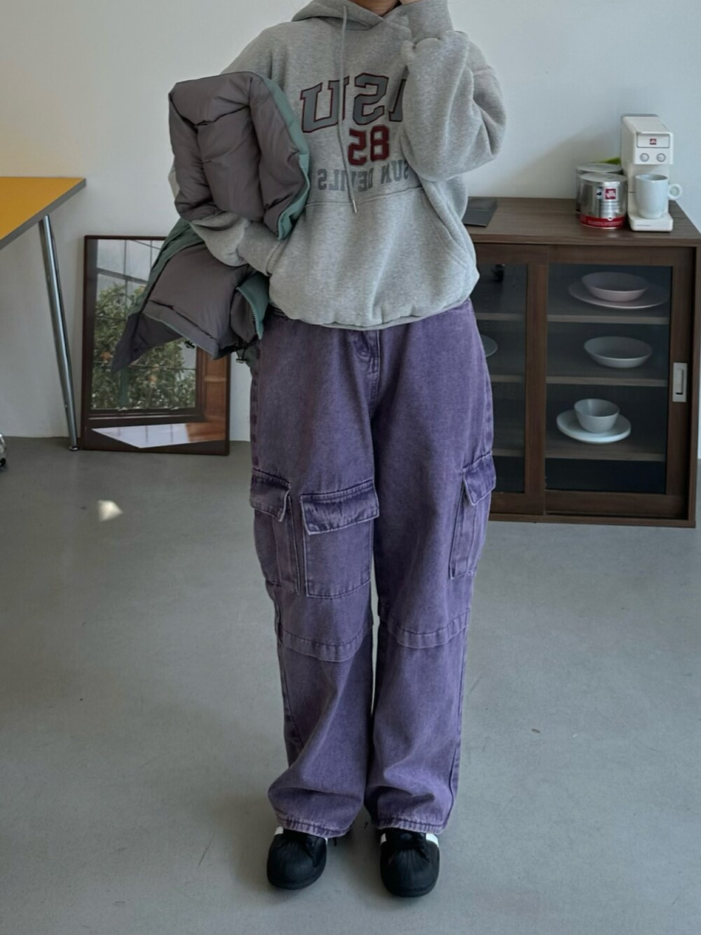 グリーン系のダウンジャケット/コート、パープル系のカーゴパンツ、ブラック系のスニーカーを着用したレディースの秋コーディネートの3枚目の写真