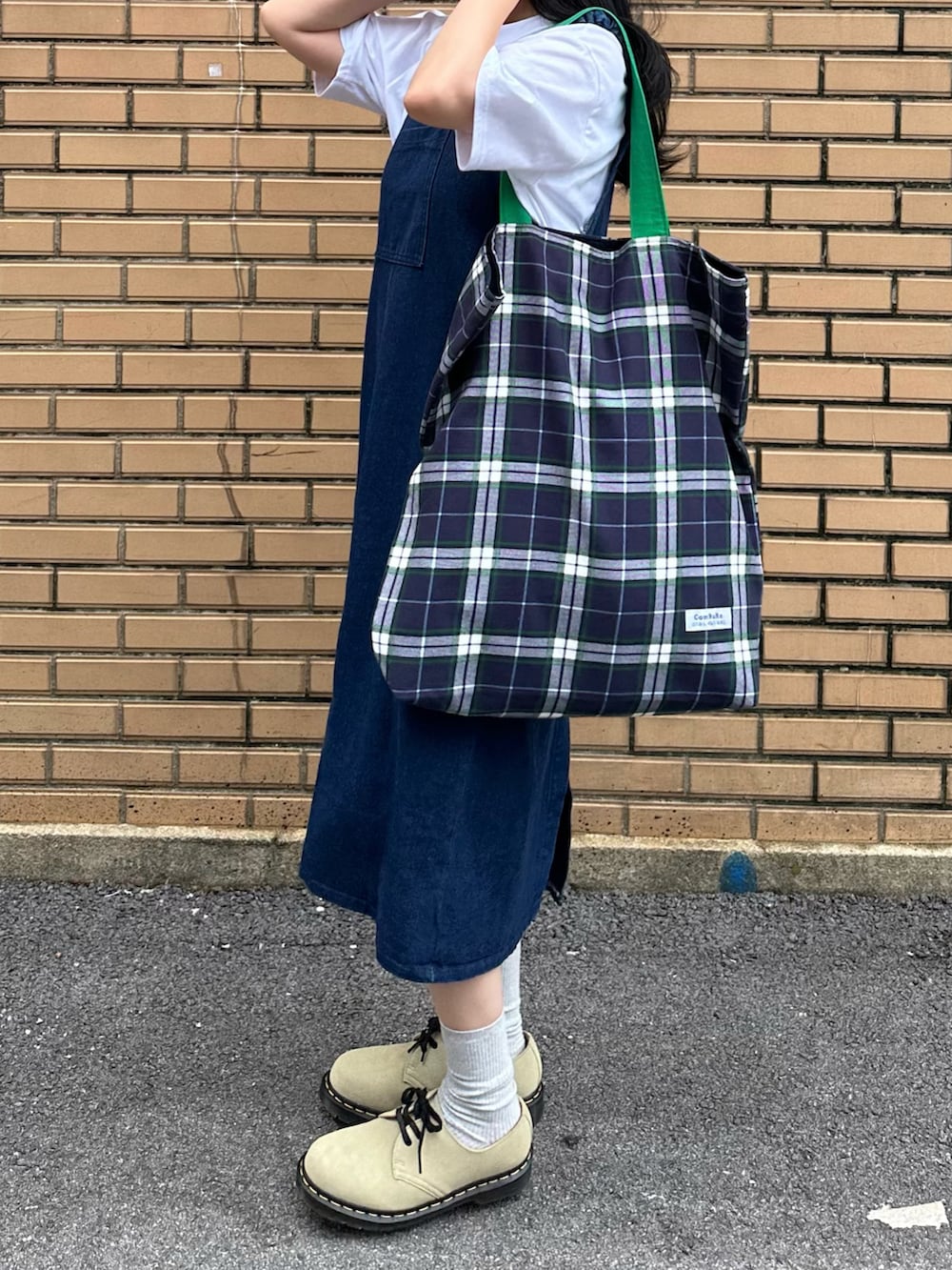 グリーン系のブーツ、ブルー系のトートバッグ、ブルー系のジャンパースカートを着用したレディースの夏コーディネートの2枚目の写真