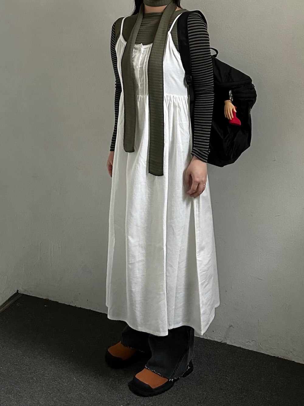 ブラック系のバックパック/リュック、ホワイト系のワンピース、グリーン系のTシャツ/カットソーを着用したレディースの春コーディネートの2枚目の写真