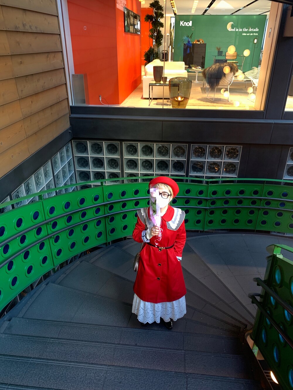 レッド系のトレンチコート、ブラック系のメガネを着用したレディースの冬コーディネートの2枚目の写真