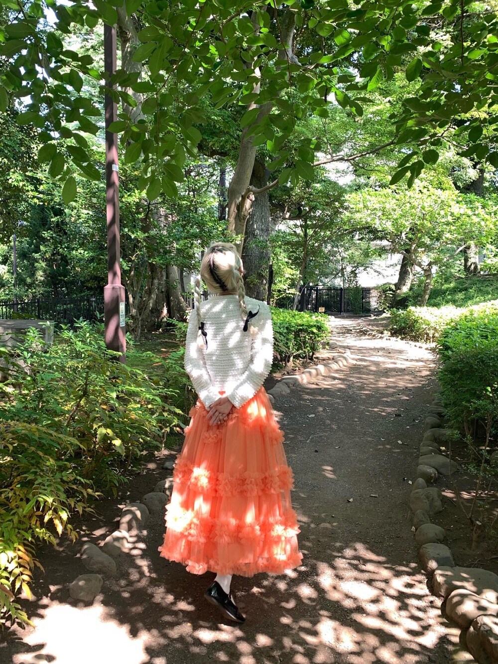 オレンジ系のスカートを着用したレディースの春コーディネートの2枚目の写真