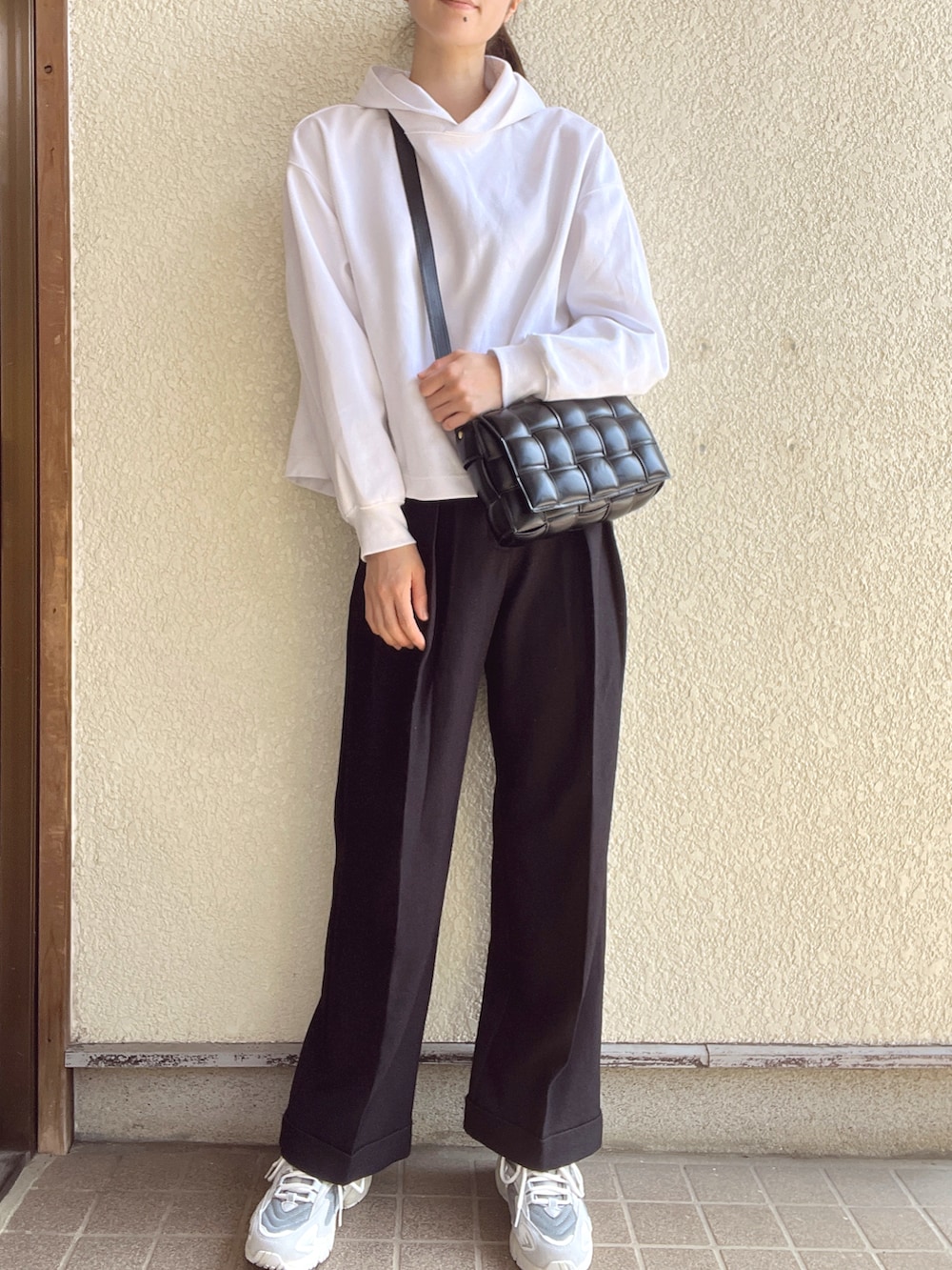 ブラック系のスラックス、ブラック系のショルダーバッグ、ホワイト系のパーカーを着用したレディースの春コーディネートの2枚目の写真