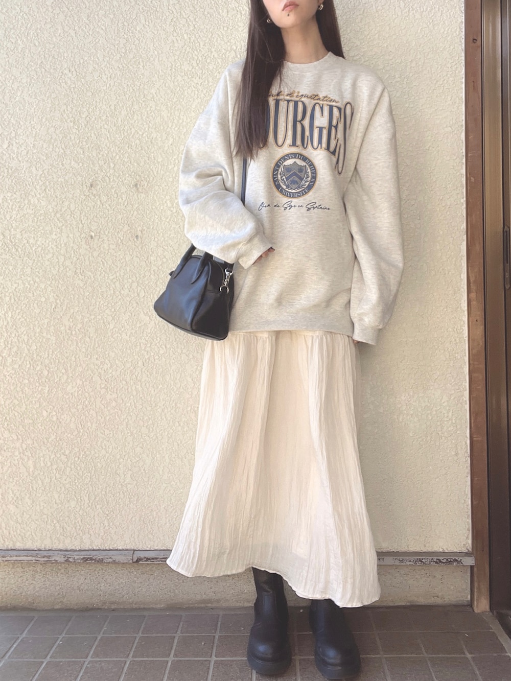 ホワイト系のスカート、ブラック系のボストンバッグ、ベージュ系のスウェットを着用したレディースの冬コーディネートの2枚目の写真