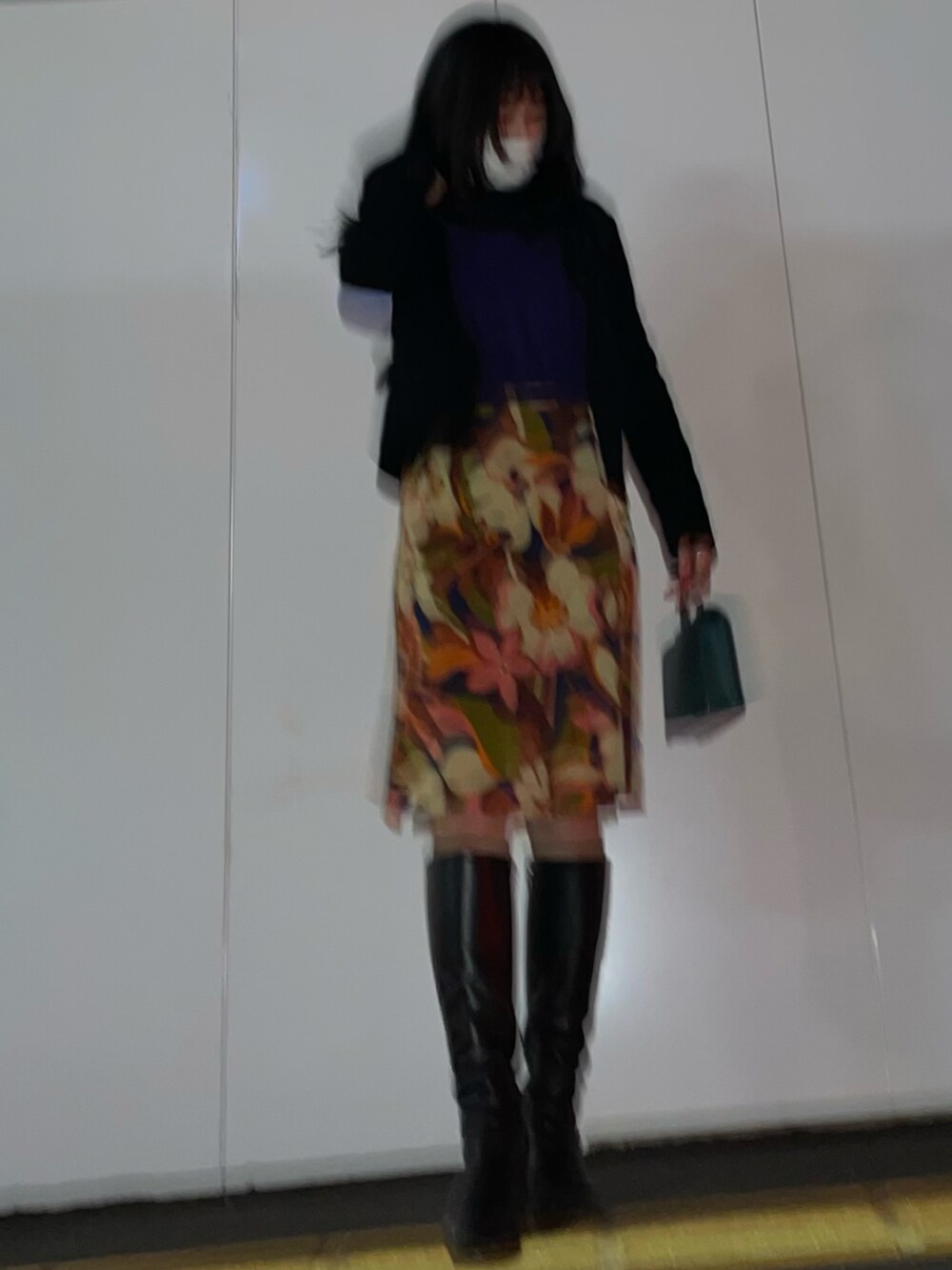 グリーン系のバッグ、ブラック系のブーツを着用したレディースの冬コーディネートの2枚目の写真