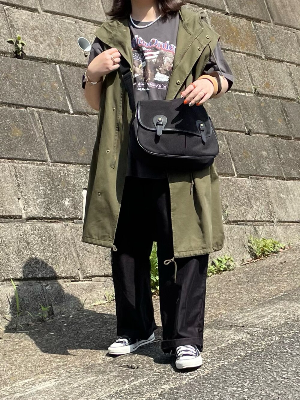 グレー系のTシャツ/カットソー、グリーン系のベスト、ブラック系のスニーカーを着用したレディースの春コーディネートの2枚目の写真