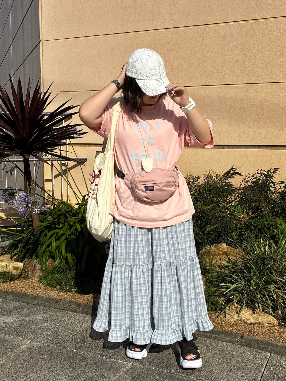 ブラック系のサンダル、ピンク系のTシャツ/カットソー、ピンク系のボディバッグ/ウエストポーチを着用したレディースの夏コーディネートの2枚目の写真