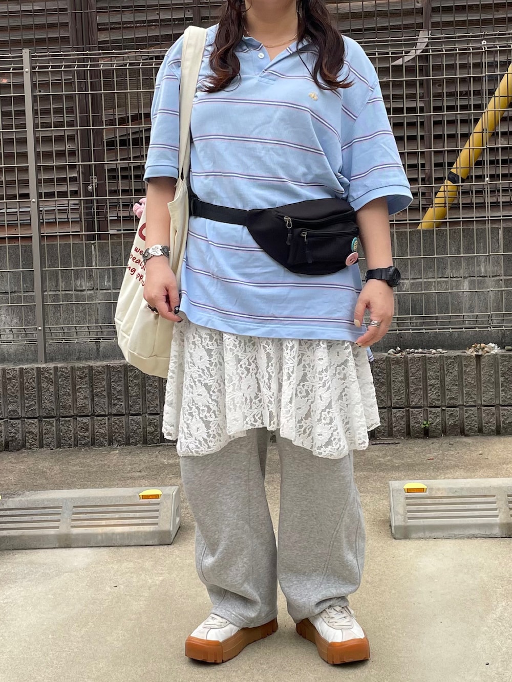 ブルー系のポロシャツ、ブラック系のボディバッグ/ウエストポーチ、ホワイト系のスニーカーを着用したレディースの春コーディネートの3枚目の写真