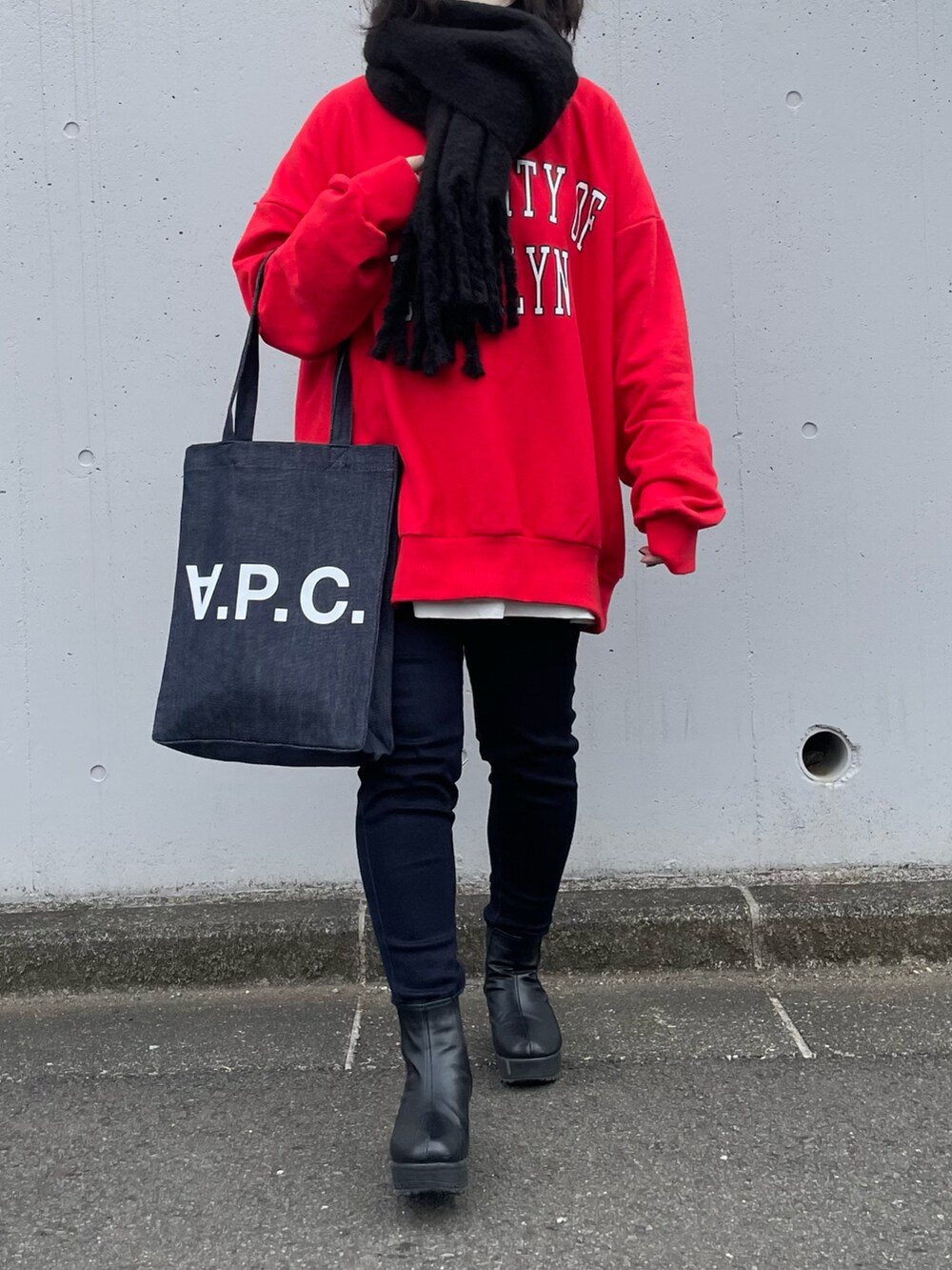 レッド系のスウェット、ブルー系のパンツ、ブルー系のトートバッグを着用したレディースの冬コーディネートの3枚目の写真