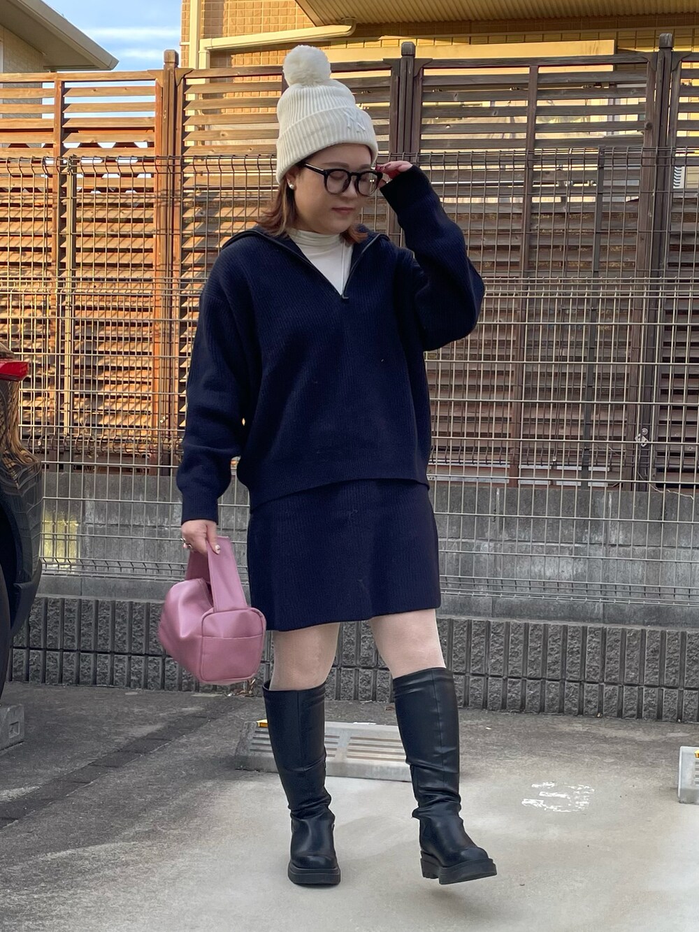 ピンク系のボストンバッグ、ブラック系のブーツ、ホワイト系のTシャツ/カットソーを着用したレディースの冬コーディネートの2枚目の写真