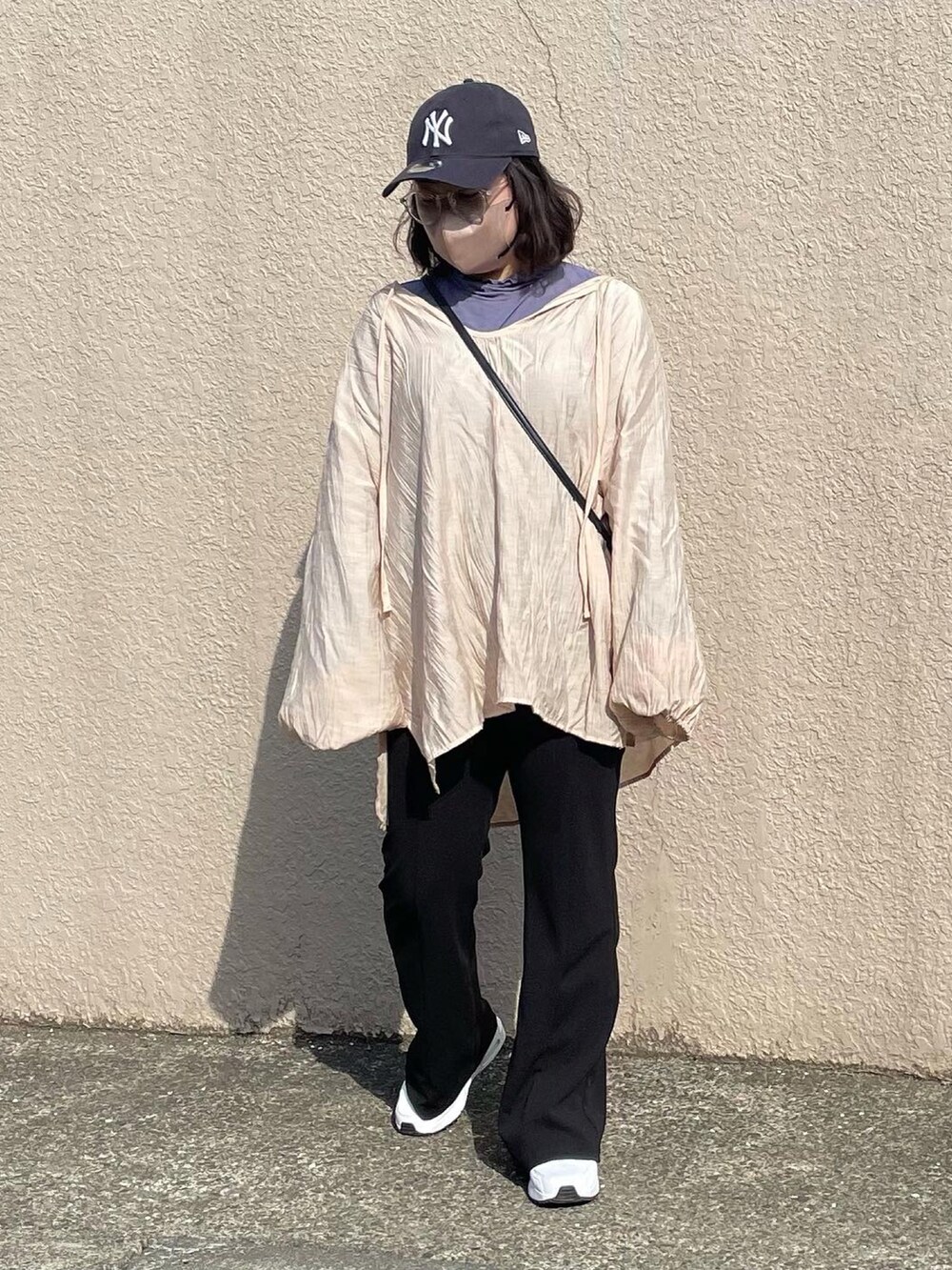 ピンク系のシャツ/ブラウス、ブラック系のパンツ、ブルー系のキャップを着用したレディースの春コーディネートの2枚目の写真