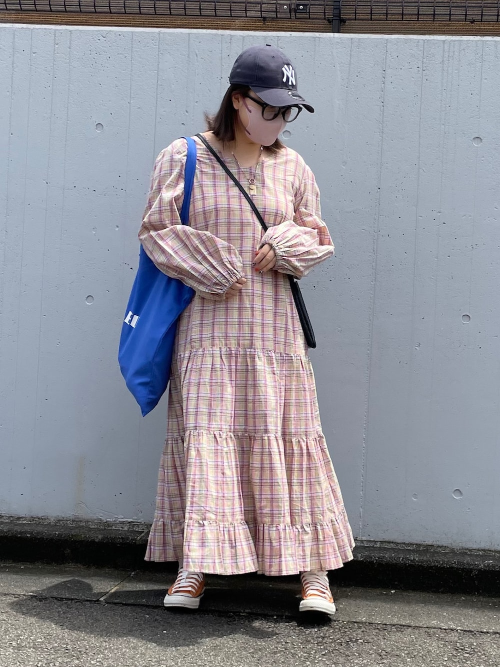 イエロー系のワンピース、ブルー系のトートバッグ、オレンジ系のスニーカーを着用したレディースの夏コーディネートの2枚目の写真